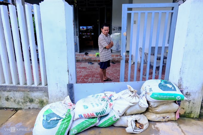 Gia đình ông Trần Viết Phúc phải dùng bao cát, tấm ván chặn cổng, xây tường gạch trước hiên nhà nhưng vẫn không ngăn được bùn đất từ cụm công nghiệp Cẩm Lệ tràn vào mỗi khi mưa lớn. Ảnh: Nguyễn Đông