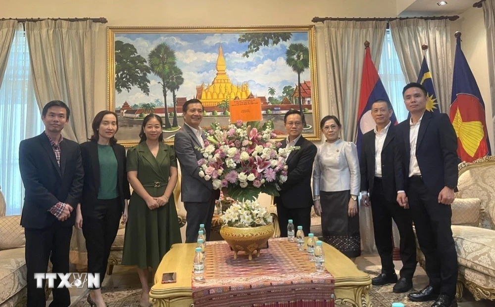 O embaixador vietnamita na Malásia, Dinh Ngoc Linh (4º à esquerda), oferece flores a funcionários e membros da equipe da Embaixada do Laos. (Foto: Thanh Trung/VNA)