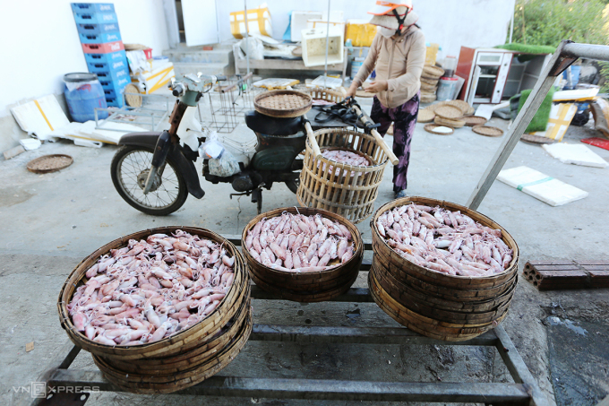 Ms. Tran Thi Yen puts baskets of steamed squid on her motorbike to sell. Photo: Son Thuy