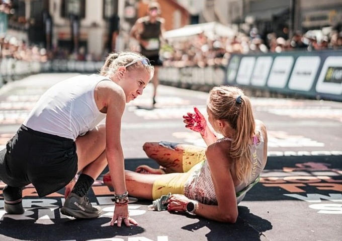 A volunteer asks Nordskar about her as she lies down on the track after the finish line. Photo: Golden Trail Series/Marathon du Mont-Blanc