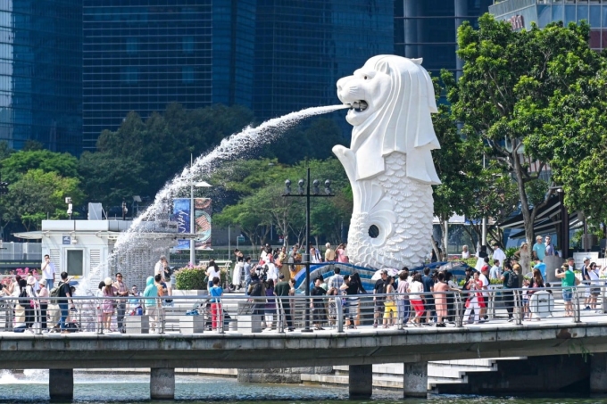 Du khách chụp ảnh trước tượng Merlion tại Singapore. Ảnh: AFP