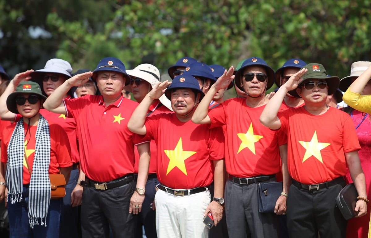 Overseas Vietnamese and delegates perform a flag-raising ceremony on Truong Sa Island. (Photo: Hong Son/Vietnam+)