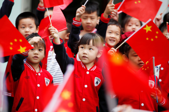 Niños en Hangzhou ondean banderas nacionales chinas mientras asisten a una ceremonia el 29 de septiembre de 2017. Foto: Reuters