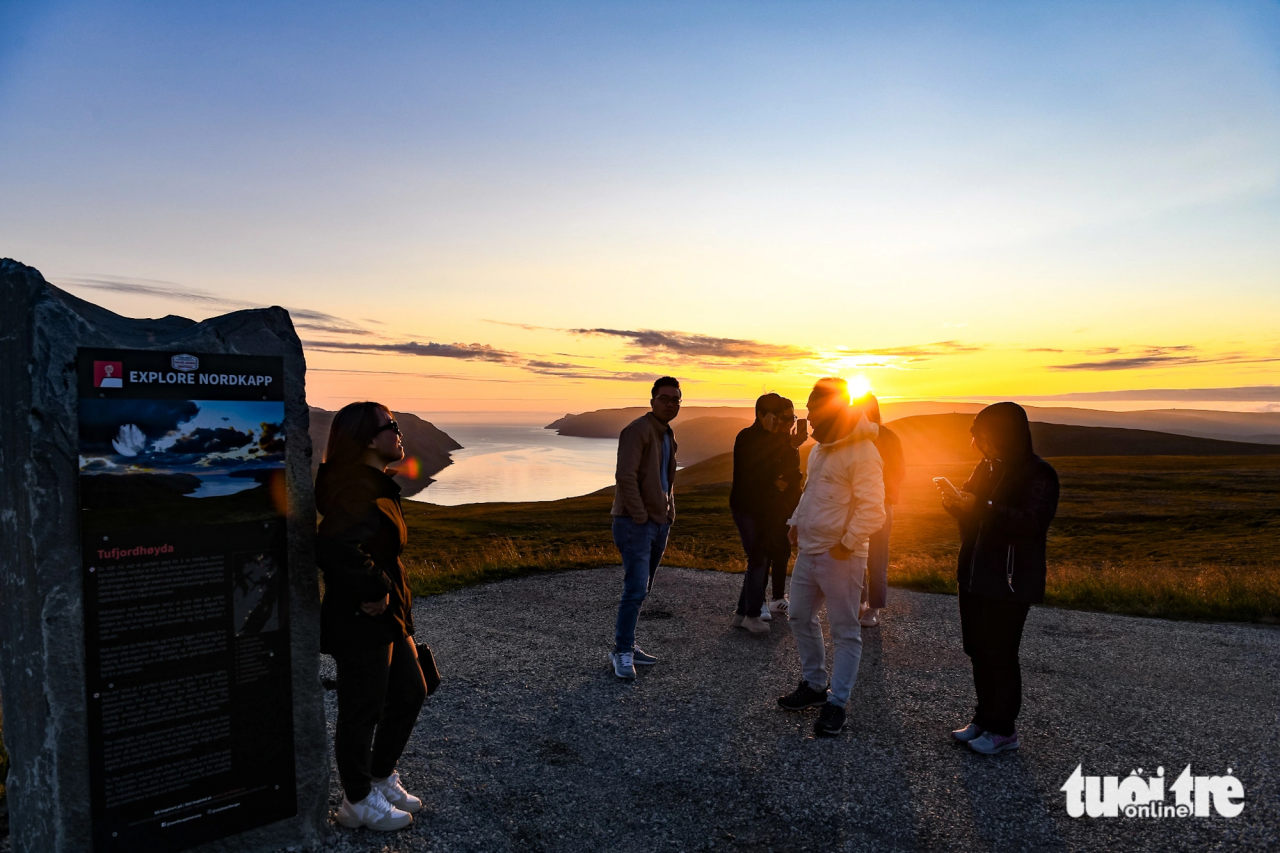 Nhóm du khách dừng chân tại một tảng đá gắn biển Explore Nordkapp trước khi đi Mũi Bắc - Ảnh: NAM TRẦN