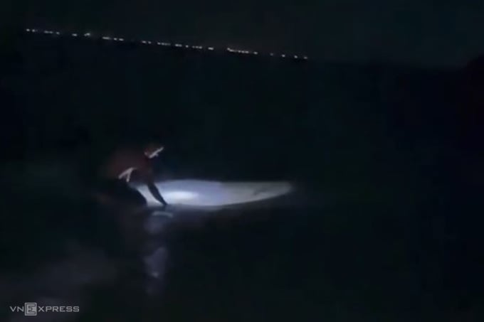 Mr. Bach shines a flashlight to catch crabs along the beach at night. Photo: Vo Thanh