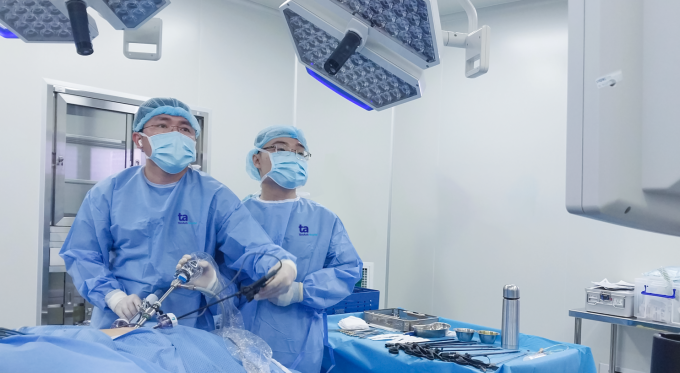 Doctor Dat (left) performs surgery to remove Ms. Nga's adrenal tumor. Photo: Thang Vu