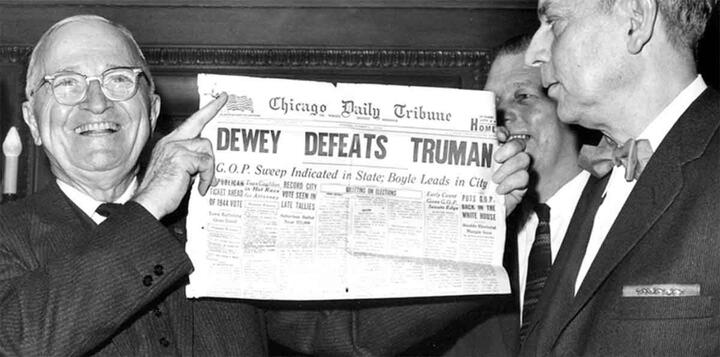 Mr. Truman holds the newspaper page that 