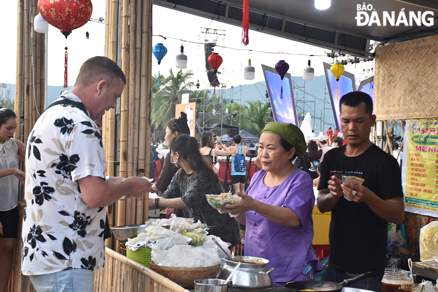 Les touristes étrangers dégustent de la nourriture lors du festival. Photo : L THU HA