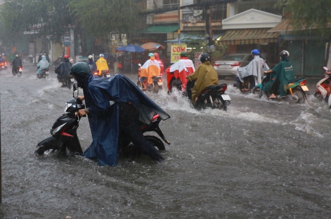 Menschen waten durch das Hochwasser, um ihre kaputten Motorräder vorzuschieben und einen Platz zu finden, wo sie repariert werden können. Foto: Minh Tuan