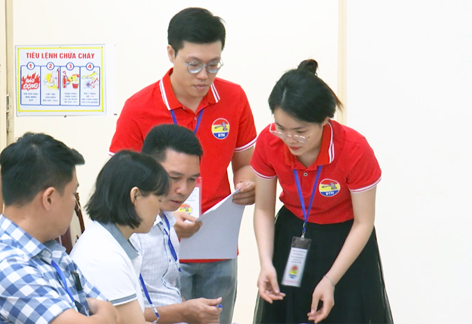 El personal de la empresa de subastas distribuye las papeletas e instruye a los inversores sobre cómo votar. Foto: Hoang Phong