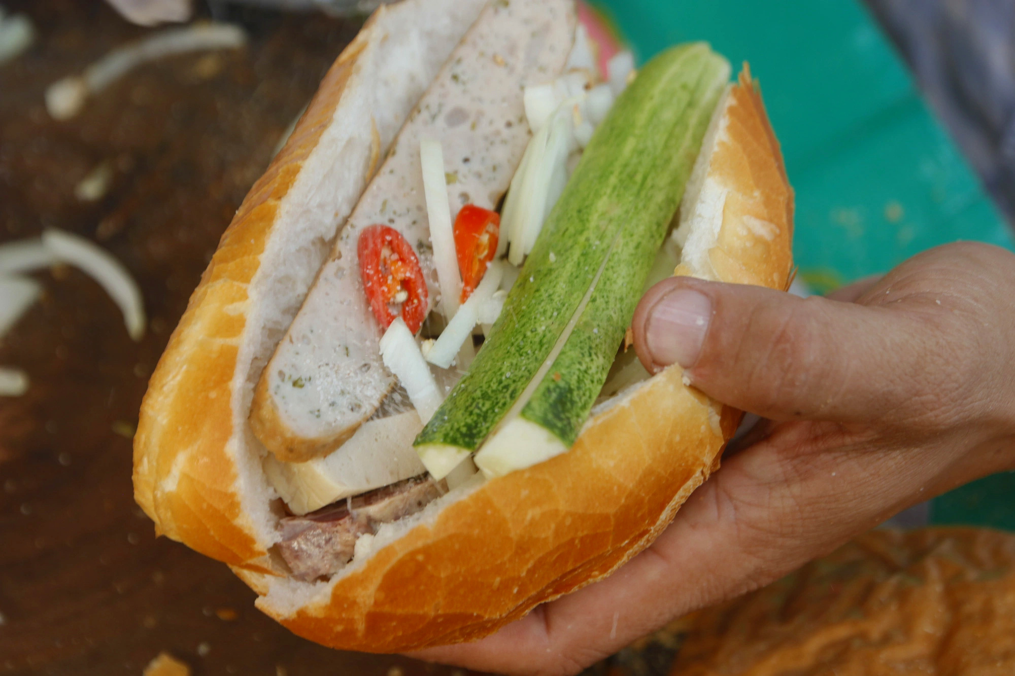 Một ổ bánh mì cụ Lý đầy đủ gồm 5 loại chả, dưa leo, ớt, hành tây, nước tương - Ảnh: HỒ LAM