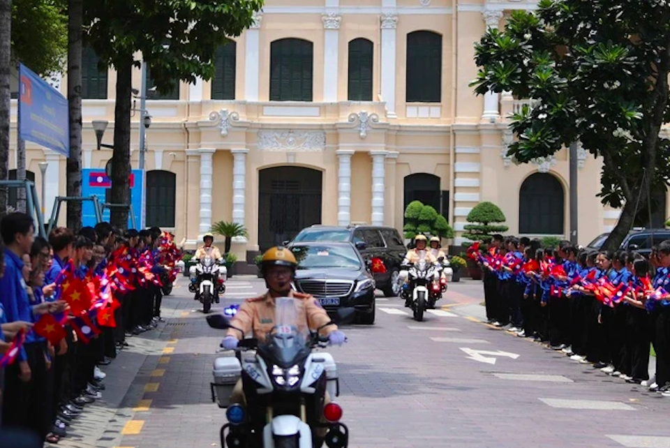 ក្បួនរថយន្តអមដំណើរអគ្គលេខាធិការឡាវ និងជាប្រធានរដ្ឋ ថងលូន ស៊ីស៊ូលីត បានមកដល់សណ្ឋាគារ REX (សង្កាត់លេខ១) ទទួលស្វាគមន៍ដោយយុវជនទីក្រុងហូជីមិញ។