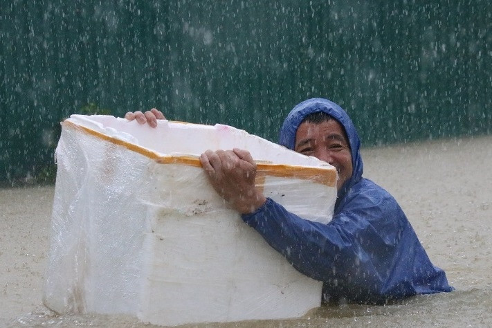 胸まで浸水したフエ市の住民は発泡スチロールの箱を担いで泳いで帰宅