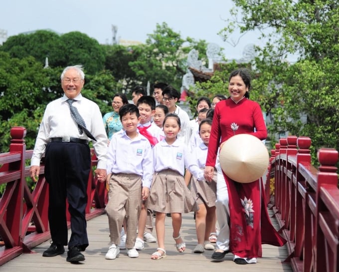 M. Vinh et Mme Duong Thi Thinh avec les élèves de l'école Nguyen Sieu au pont The Huc, à côté de la Pen Tower - le symbole du logo de l'école. Photo : fournie par l'école