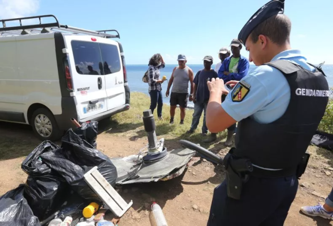 Un gendarme francés toma una fotografía de escombros en la Isla Reunión el 11 de agosto de 2015. Parte del ala fue encontrada en la isla a finales de julio de 2015 y se confirmó que pertenecía al Boeing 777 que desapareció el 8 de marzo de 2014. Foto: Richard Bouhet/AFP