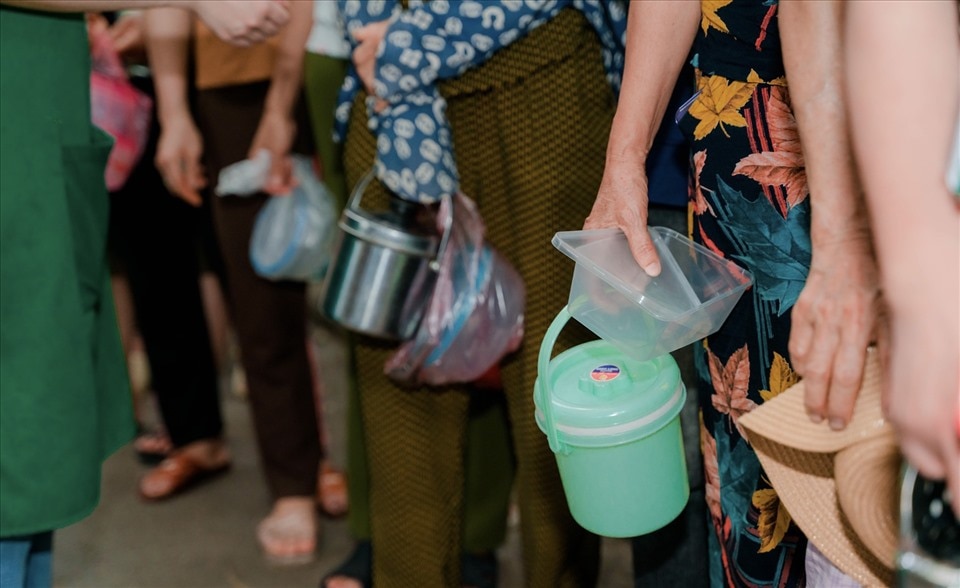 Mỗi người tới nhận cơm sẽ cầm theo cặp lồng hoặc hộp nhựa. Ảnh: Duy Nghĩa