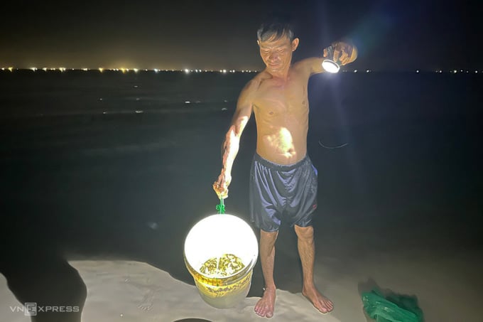 Mr. Bach shows off the finished product of half a bucket of crabs he just caught. Photo: Vo Thanh