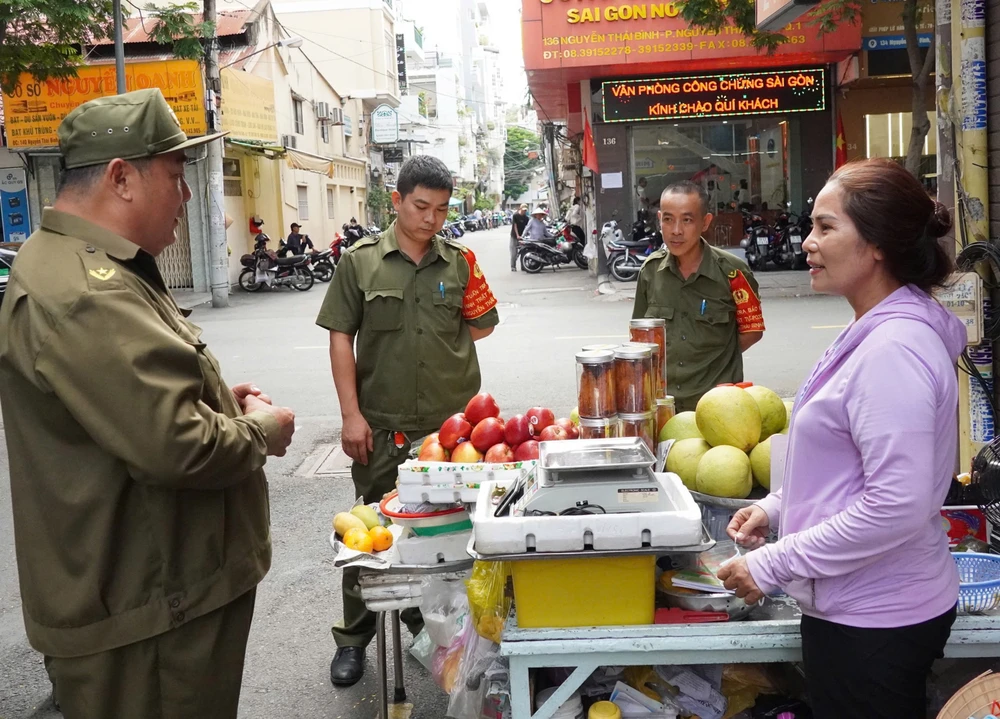 第1区グエンタイビン区の治安部隊が人々と話をしている。写真: THU HUONG