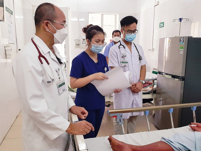 PGS.TS Đỗ Duy Cường (trái) thăm khám cho bệnh nhân sốt xuất huyết. Ảnh: Mai Thanh