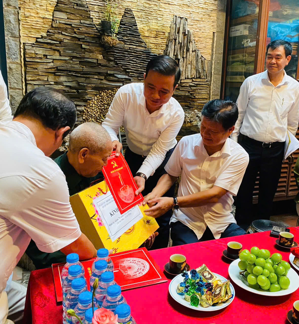 Head of the Hanoi Party Committee's Organization Committee Vu Duc Bao (second from right) presents a gift to veteran Nguyen Kim Dong, who took over the capital.