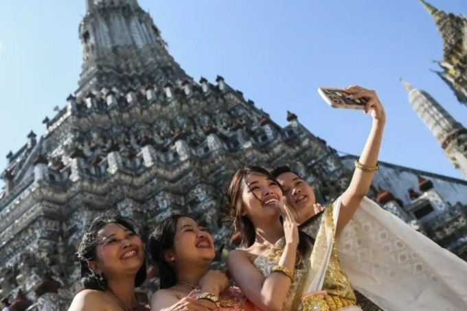 Los turistas vietnamitas visten ropa tradicional tailandesa y toman fotografías en el templo Wat Arun. Foto: Reuters