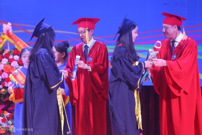 Leaders of Hanoi National University of Education presented graduation books and flowers to the new graduates. Photo: Duy Tam
