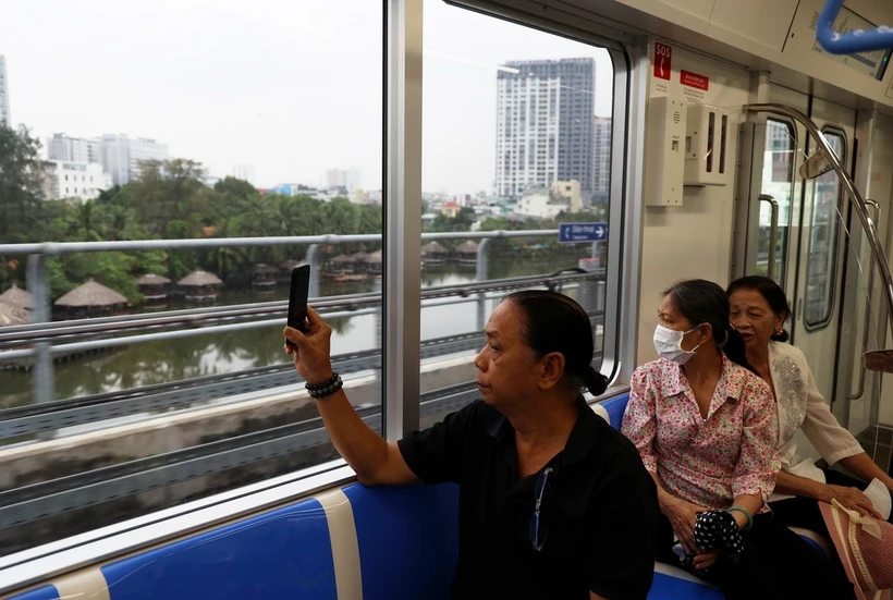 People capture images of the urban area outside when experiencing metro line 1. (Photo: Huyen Trinh/VNA)