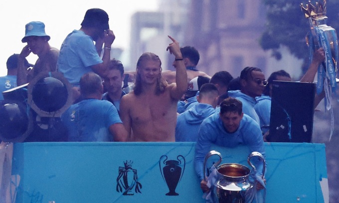 Haaland (cởi trần) phấn khích trong lễ diễu hành trên xe bus mui trần ở Manchester, mừng cú ăn ba của Man City. Ảnh: Reuters