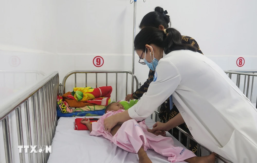 Ärzte im Kinderkrankenhaus 1 untersuchen einen kambodschanischen Kinderpatienten nach einer Herzoperation. (Foto: Dinh Hang/VNA)