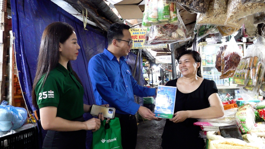 Los miembros jóvenes escanean códigos QR a comerciantes en el mercado central de Cam Pha.