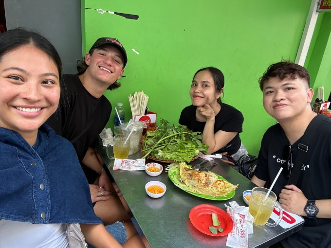 Les touristes étrangers dégustent du banh xeo avec des étudiants à Ho Chi Minh-Ville. Photo : Elle D