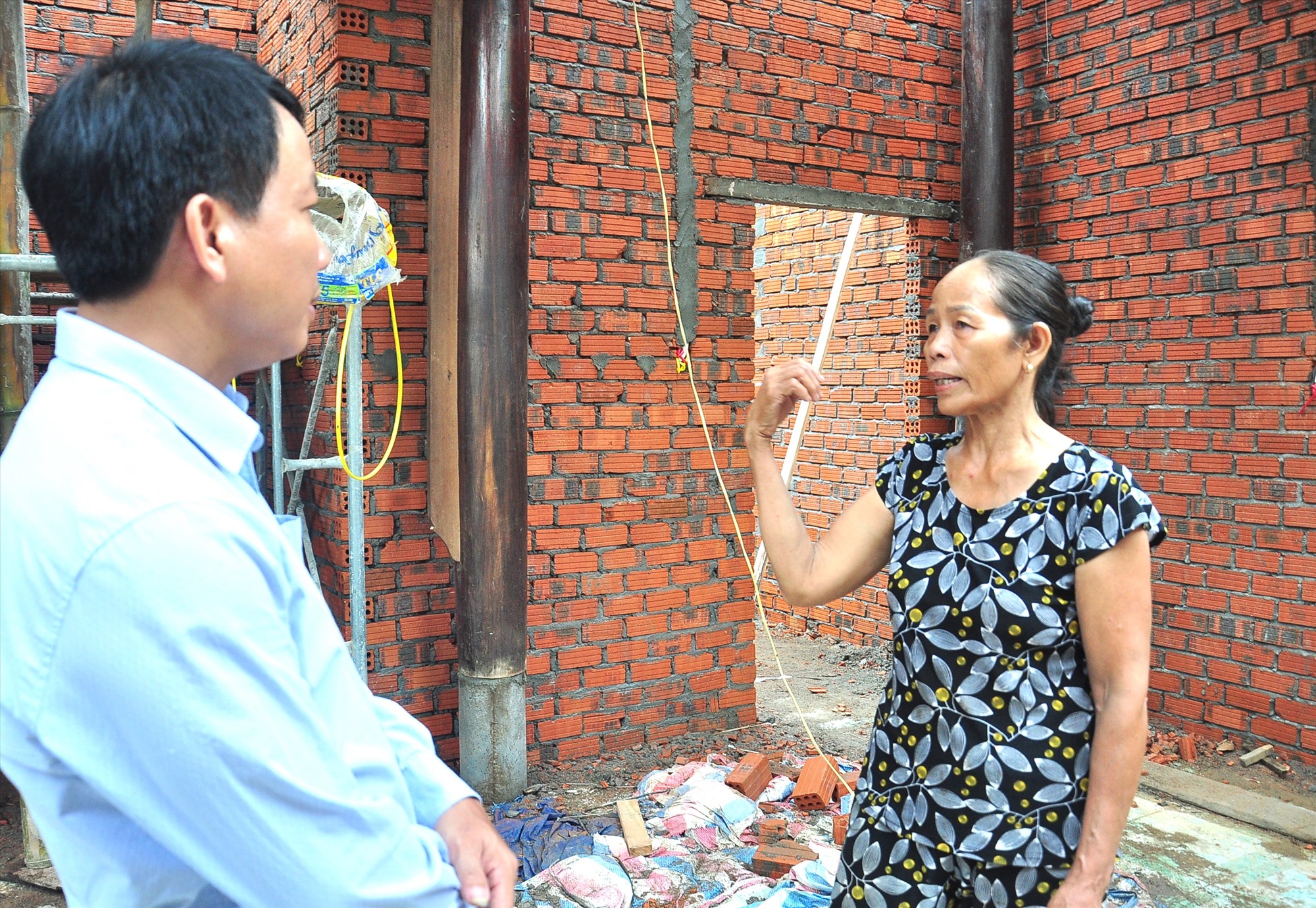 Ms. Tran Thi Tho talks with leaders of the Ninh Phuoc Commune Front inside her family's house under construction. Photo: PV