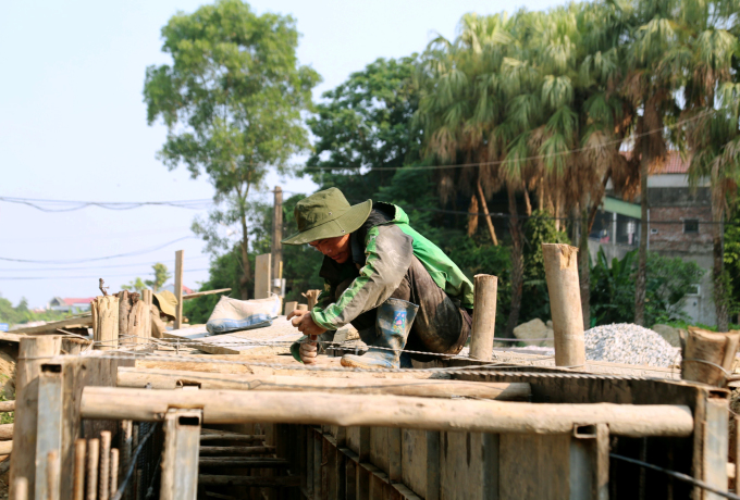 Los trabajadores construyen la carretera ampliada de Le Duan, a través de la ciudad de Ha Tinh, bajo el sol del mediodía. Foto: Duc Hung