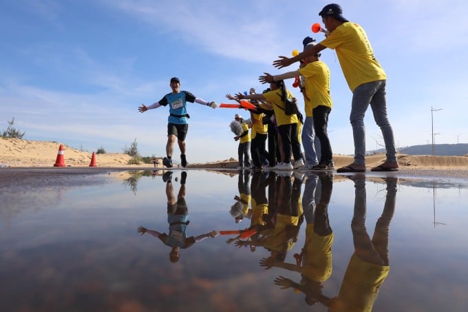 Volunteers cheer on runners as they run through the sand dunes. Photo: VM