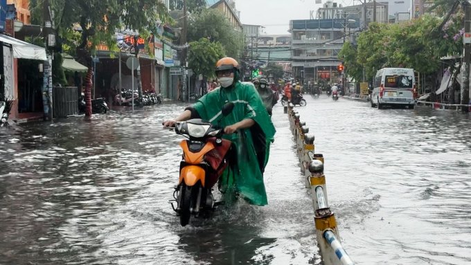 Người dân bì bỡm dắt xe chết máy qua nước ngập nửa bánh xe. Ảnh: Đình Văn