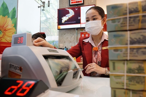 Un empleado bancario revisa el depósito de ahorros de un cliente (foto ilustrativa). Foto: HOANG HUNG