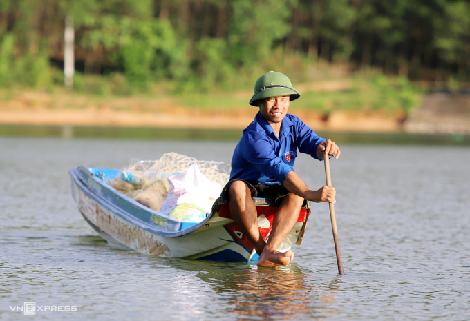 Mr. Dang Van Tu rowed a boat to check fish cages at Khe La dam. Photo: Duc Hung