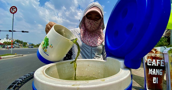 ホーチミン市の住民は、道路脇で水のボトルで涼みながら、日差しから身を守るのに苦労している。