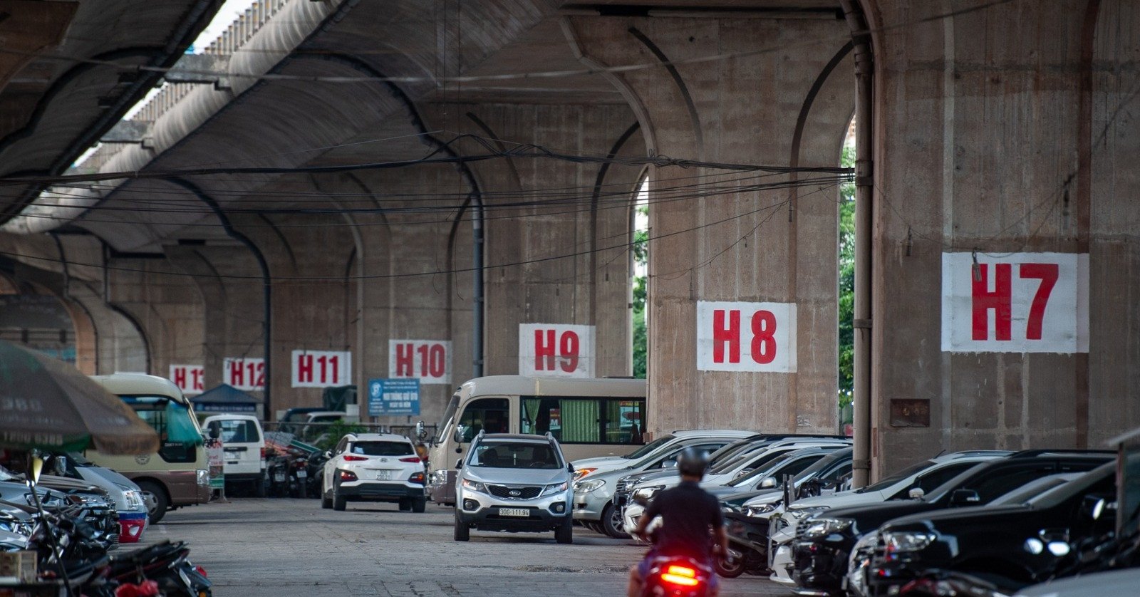 Contrasting scenes at parking lots under Hanoi overpasses