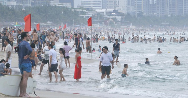 La gente de Da Nang acude en masa a la playa para refrescarse, los turistas occidentales surfean con entusiasmo