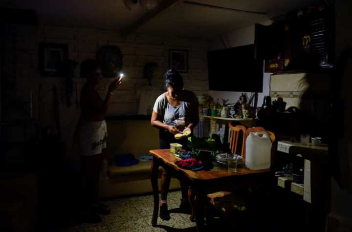 10月18日、キューバのハバナで、携帯電話のライトを頼りに料理をする女性。 （写真：ロイター）