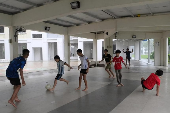 Des enfants jouent au football dans l'espace communautaire du rez-de-chaussée d'un immeuble HDB à Woodlands, Singapour. Photo : ST