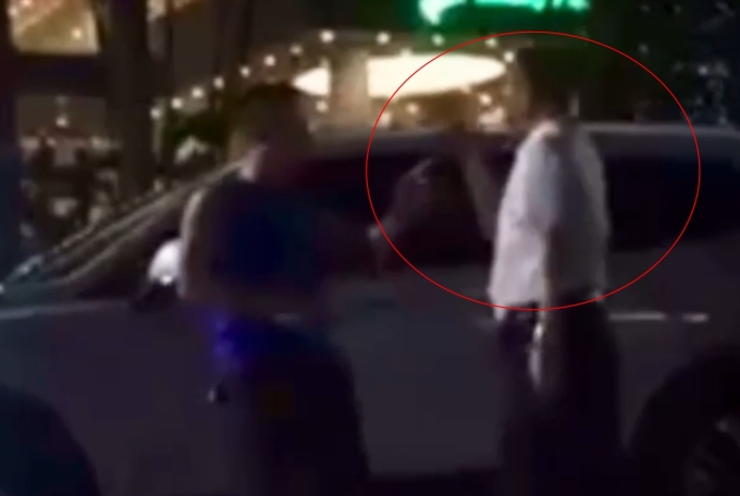 Mr. Nam (in white shirt) threatens people after a traffic accident. Photo cut from clip.