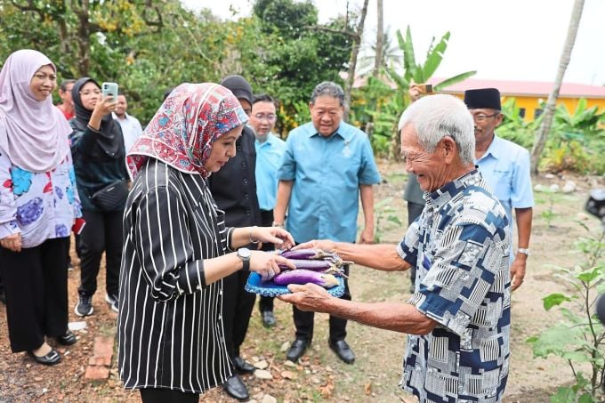 Queen Raja receives a gift of freshly harvested eggplants from low-income resident Mr Loh in 2023. Photo: Star