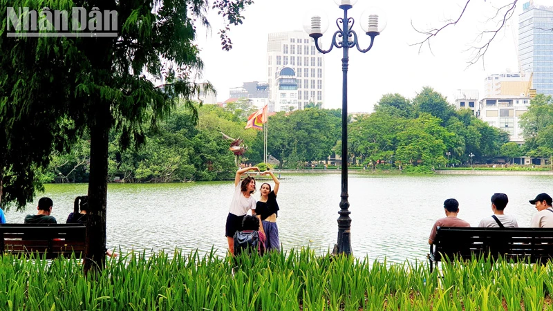 Des touristes étrangers prennent des photos au lac Hoan Kiem, à Hanoi (Photo : T.LINH)