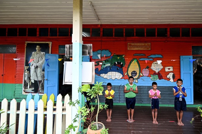 Cuatro estudiantes saludan a la bandera por la mañana en una escuela en Ban Khun Samut Chin, el 14 de junio. Foto: AFP