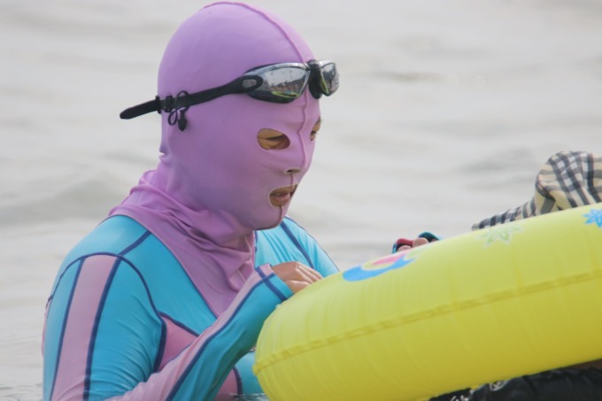 Una mujer lleva un traje de baño protector solar de cuerpo entero, que solo deja al descubierto sus ojos y fosas nasales, en Qingdao, provincia de Shandong, el 15 de agosto de 2020. Foto: VCG
