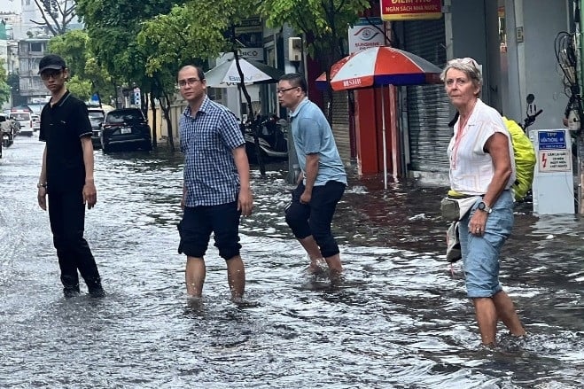 ນັກ​ທ່ອງ​ທ່ຽວ​ນຸ່ງ​ໂສ້ງ​ເສື້ອ​ອອກ​ເດີນ​ທາງ​ຜ່ານ​ນ້ຳ​ຖ້ວມ​ຢູ່​ນະ​ຄອນ HCMC