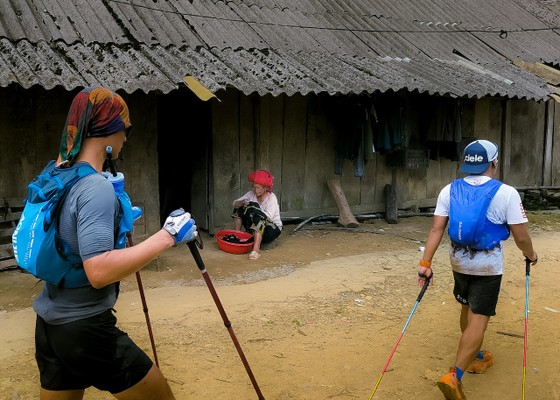 Người phụ nữ đồng bào ngồi vá áo, lọt vào khung hình khi hai vận động viên 100km đi qua ảnh 11