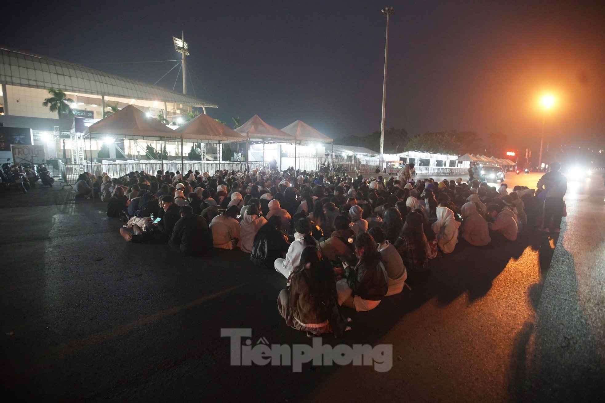 Long lines of spectators covered in scarves, sitting and sleeping right in front of My Dinh Stadium photo 1